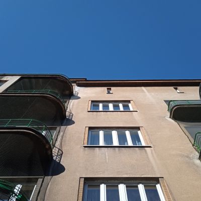 Do wykończenia ścian powyżej parteru użyto barwionego w masie tynku cyklinowanego (zacieranego na gładko) z dodatkiem odbijającej światło "miki", dzięki kt&oacute;rej elewacja do dziś "ożywa" i błyszczy w słoneczne popołudnia.  W gładkim tynku odcinają się wyraźnie dłutowane pionowe i poziome elementy podkreślające glify okienne, podesty balkon&oacute;w i gzyms wieńczący. Uważne oko dostrzeże tu także kasetonowe płyciny pod okapem dachu. Zdjęcie ze zbior&oacute;w Biura Miejskiego Konserwatora Zabytk&oacute;w UM Rzeszowa